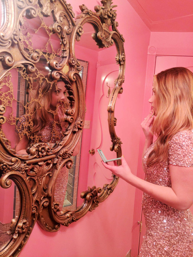 woman putting on makeup in mirror